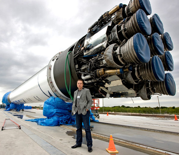 Elon Kusk posa ao lado de um dos seus foguetes Falcon.